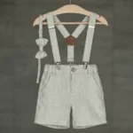 Boys linen shorts with suspenders and bow tie in light grey, hanging on a wooden hanger