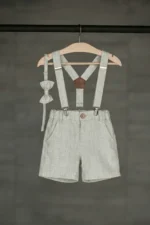 Boys linen shorts with suspenders and bow tie in light grey, hanging on a wooden hanger