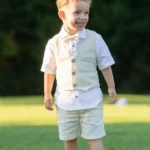 Boy wearing a linen suit set with vest, short-sleeve shirt, bow tie, and shorts outdoors