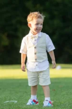 Boy wearing a linen suit set with vest, short-sleeve shirt, bow tie, and shorts outdoors