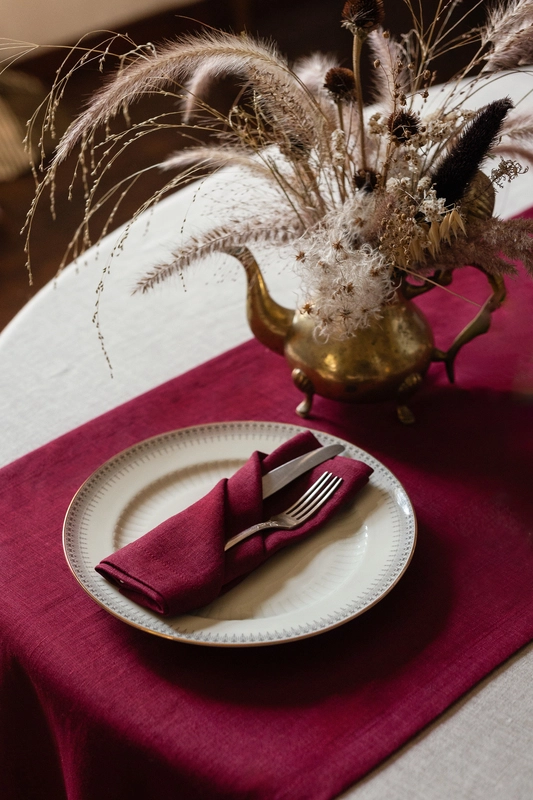 Burgundy linen table runner styled on a table for elegant event decor