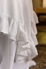 White linen ruffled tablecloth draped on a round table with soft layered hem