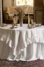 Square white linen overlay with ruffled edges layered on a round table