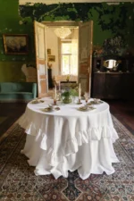 Square white linen tablecloth styled on a small round table