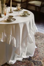 White linen tablecloth styled on a round wedding table with classic decor