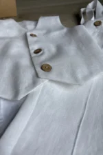 White linen christening outfit for baby boy with natural fabric texture and wooden buttons